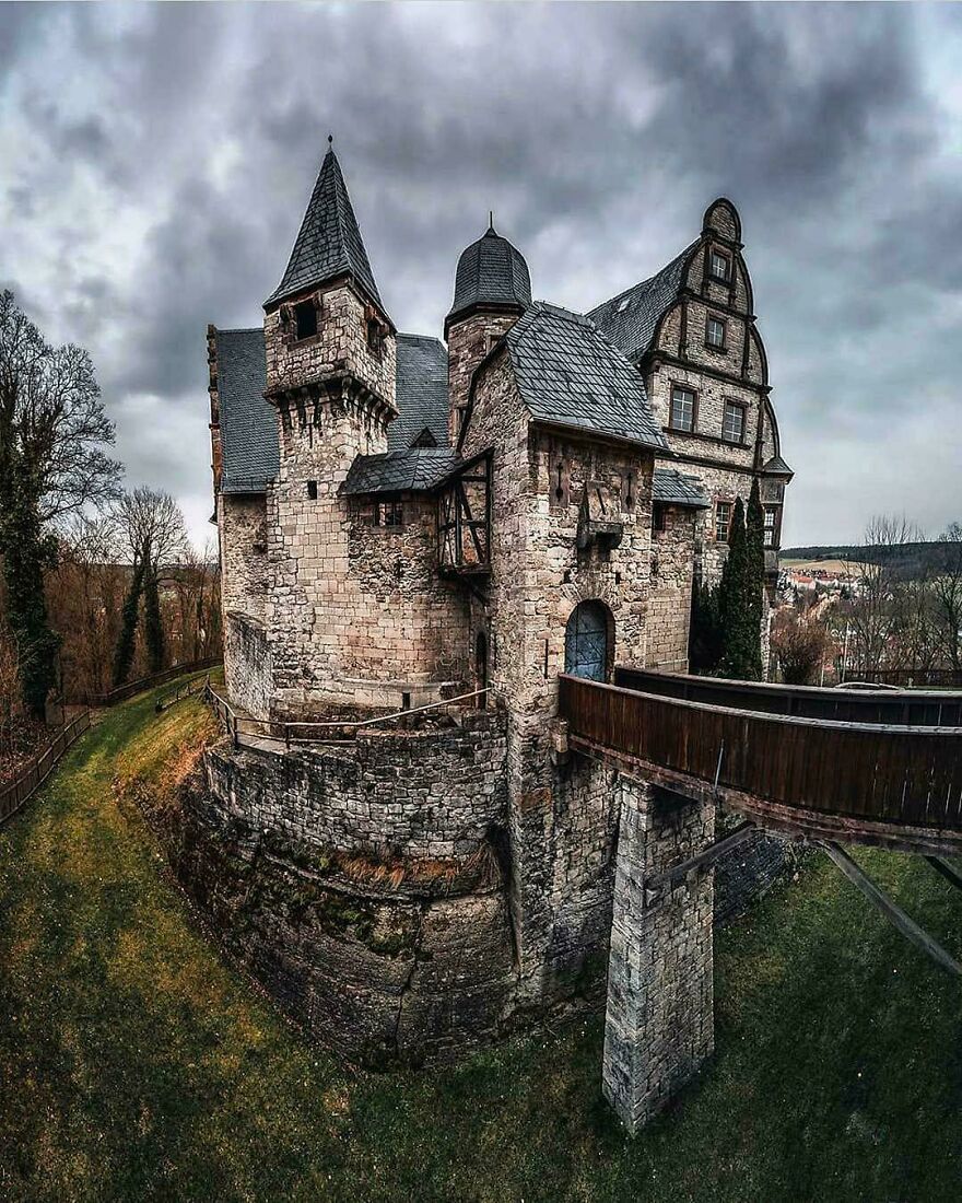 An interesting medieval castle with a stone bridge under a dramatic cloudy sky, highlighting the beautiful architecture.