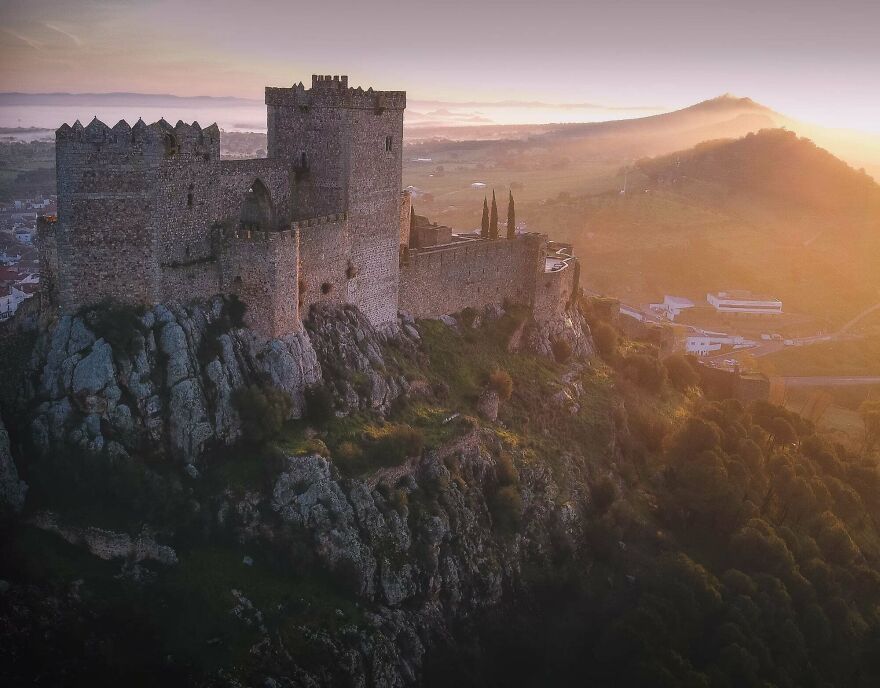 Beautiful castles photos: A stone castle at sunset, perched on a mountain, with mist in the valley. Interesting and dramatic view.