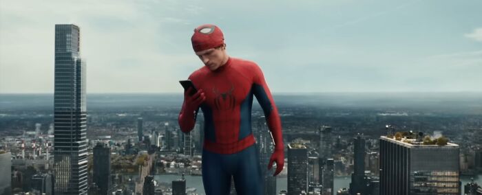 Spider-Man on a skyscraper looking at his phone with a cityscape background, illustrating nonsensical movie details.