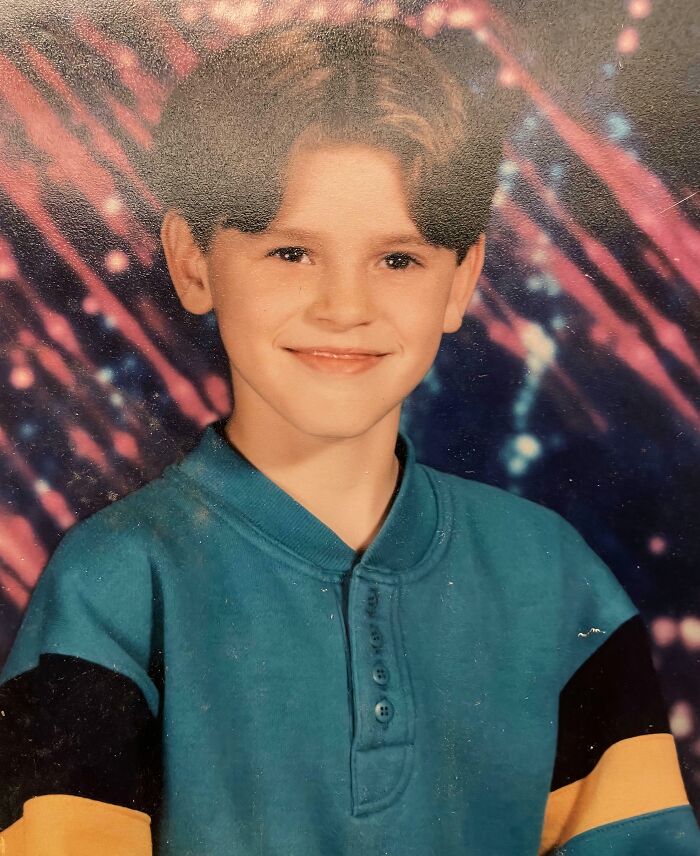 A young 90s kid with a classic haircut smiles for a school photo, a relatable image for throwback memes.