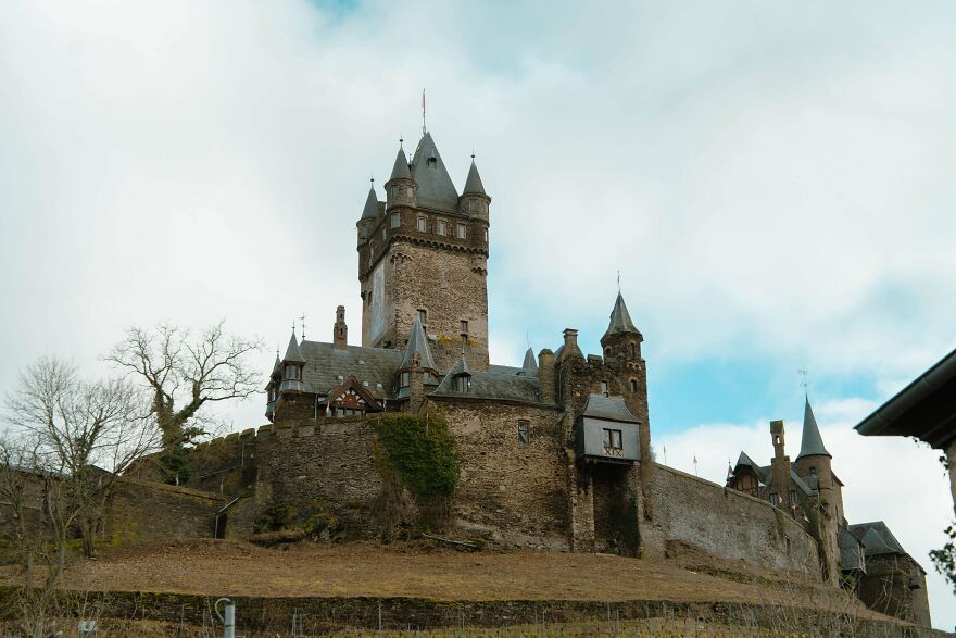 Beautiful stone castles perched on a hill, with intricate architecture and pointed towers under a bright sky.