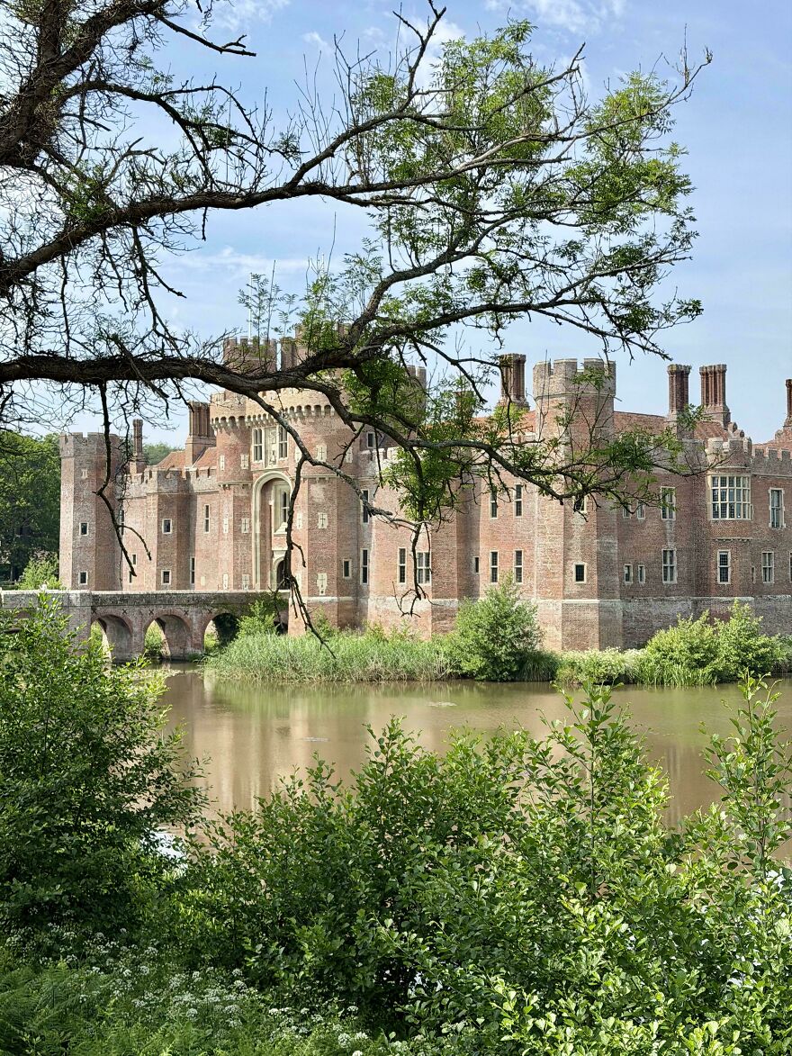 Interesting brick castles with a bridge over a moat, surrounded by lush green trees and foliage.