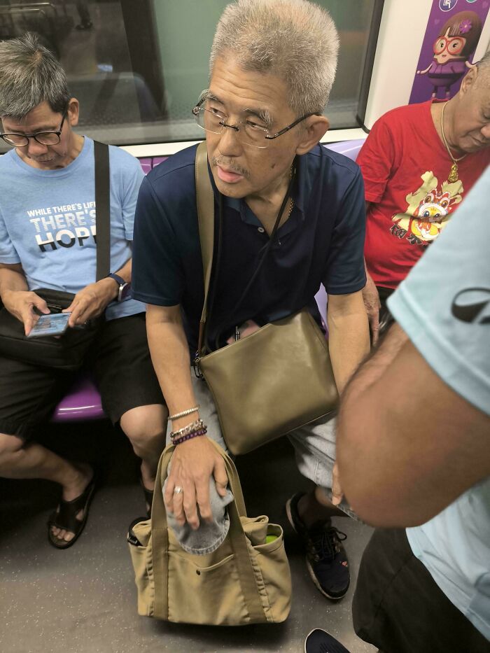 Elderly man on a subway, sitting next to other passengers. Entitled men often ignore personal boundaries.