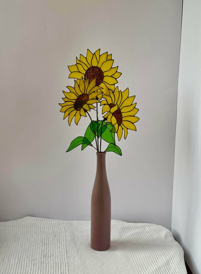 A vase with three handmade stained-glass sunflowers, an elegant and talented project.