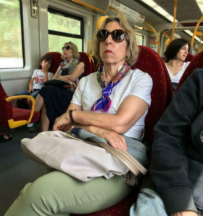 A woman on a train with a handbag, creating an optical illusion that makes her legs appear disproportionate.
