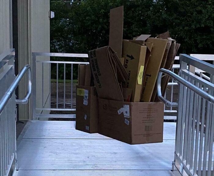 An optical illusion of cardboard boxes suspended in mid-air on a concrete ramp.