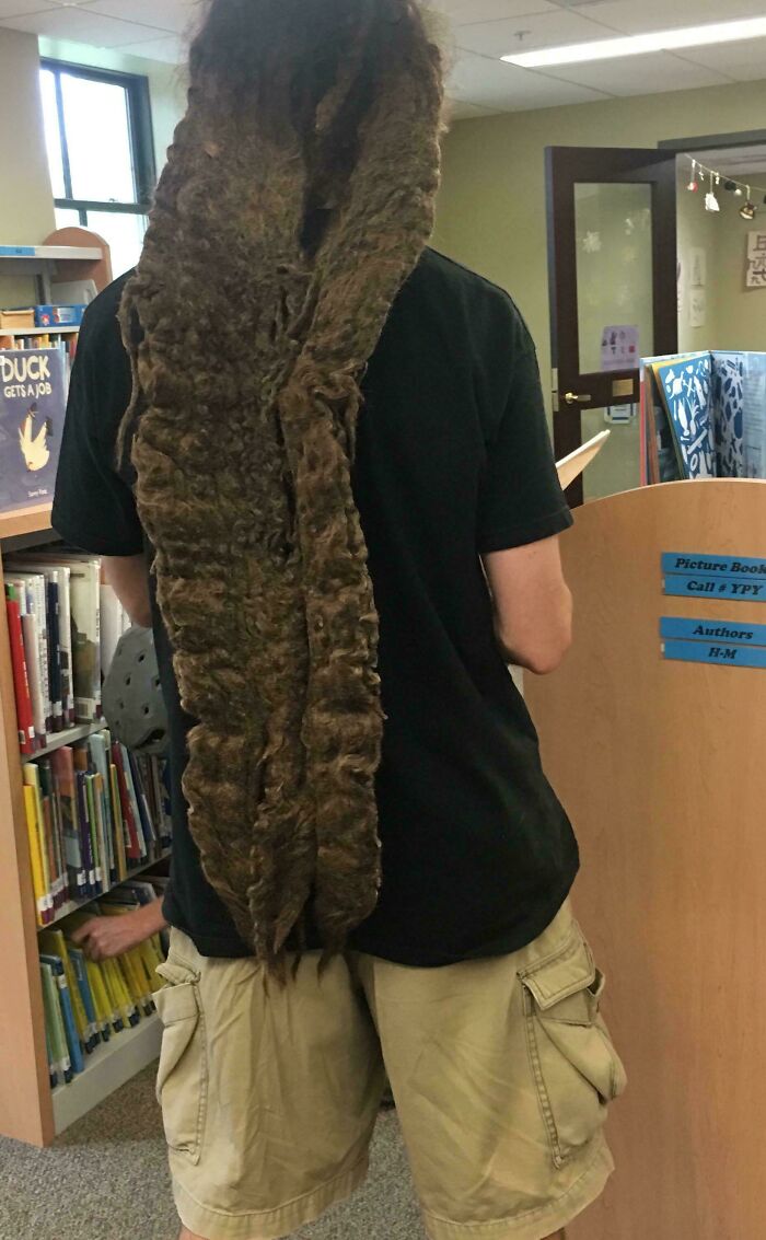 Man from behind with extremely long, thick dreadlocks extending to his knees, a bad hair mistake.