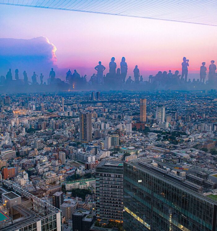 Cityscape with giant silhouetted figures on the horizon, creating a real life optical illusion.