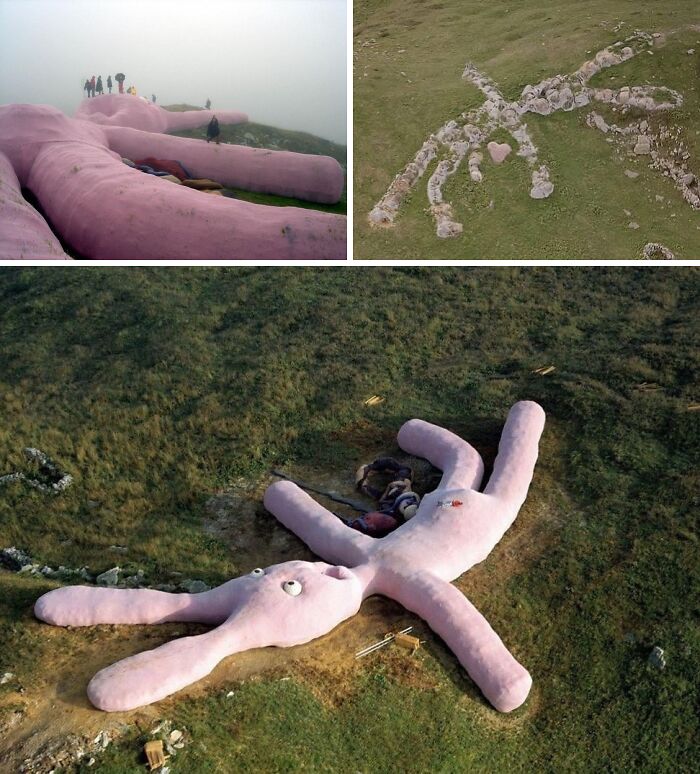 Large pink rabbit-shaped land art installation on a grassy hill