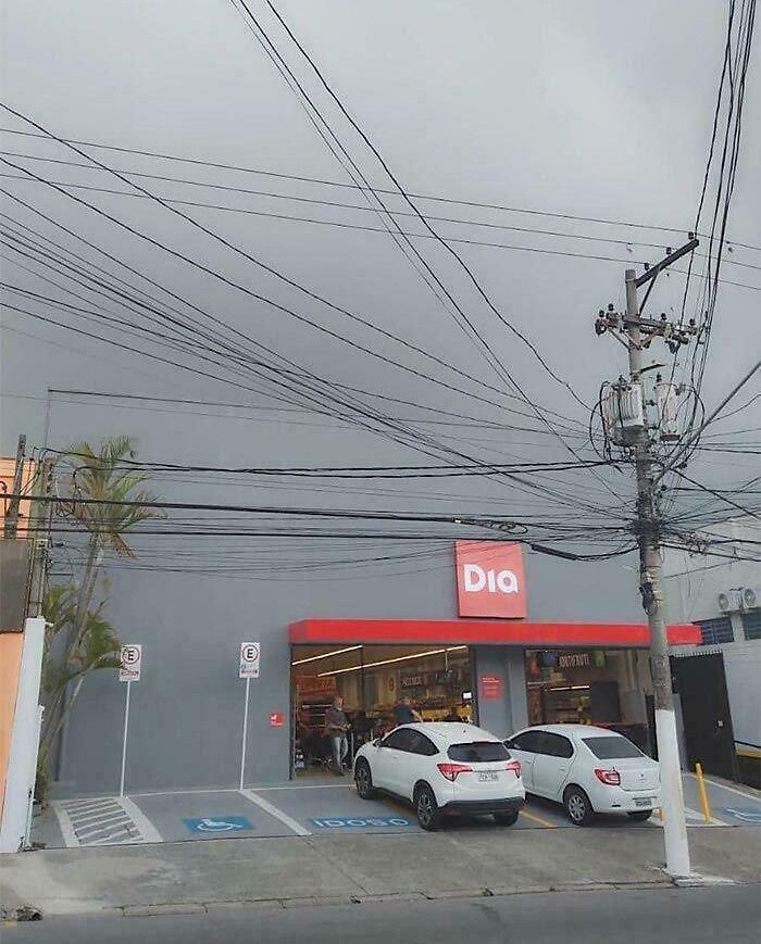 A grocery store with an abundance of crisscrossing power lines overhead, creating an optical illusion.