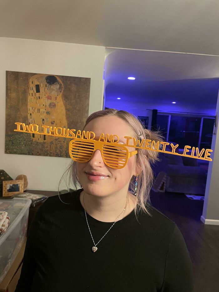 A person wearing novelty orange 3D printed glasses that spell out 'Two Thousand and Twenty Five', a fun 3D printer project.