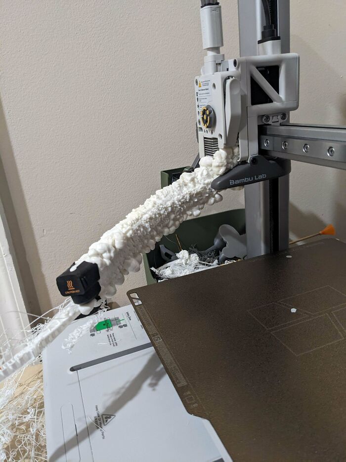 A 3D printer covered in a large amount of white, foamy filament, illustrating an interesting 3D printer project.