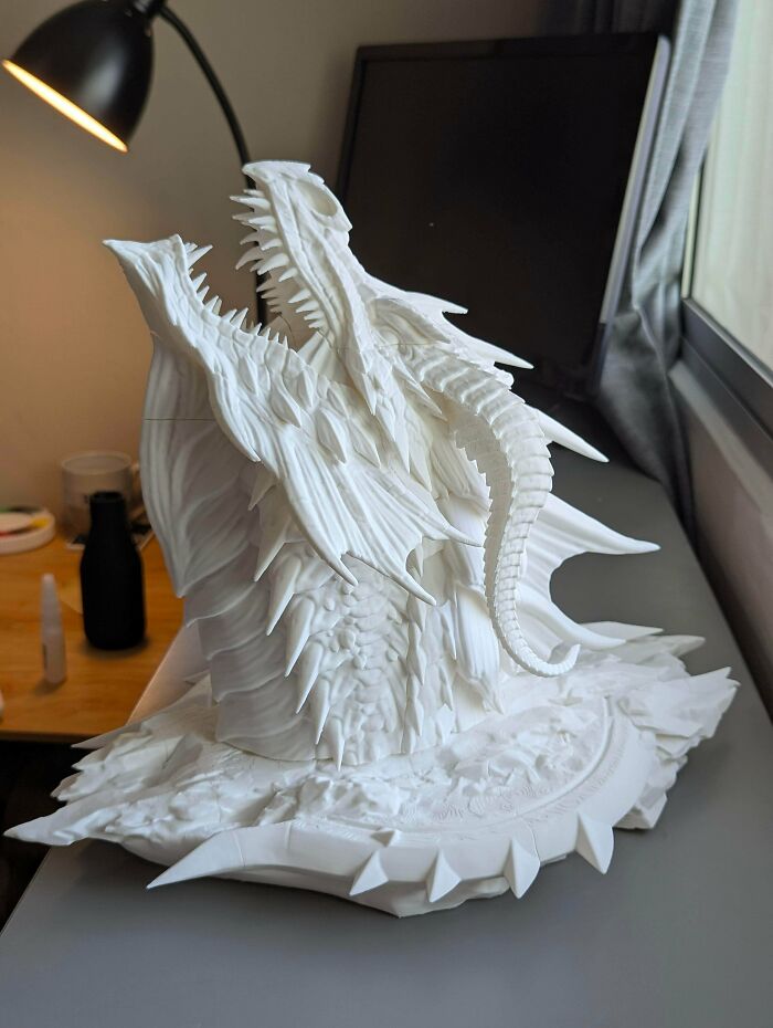 An intricate white 3D printed dragon head sculpture with sharp teeth and scales, among coolest projects.