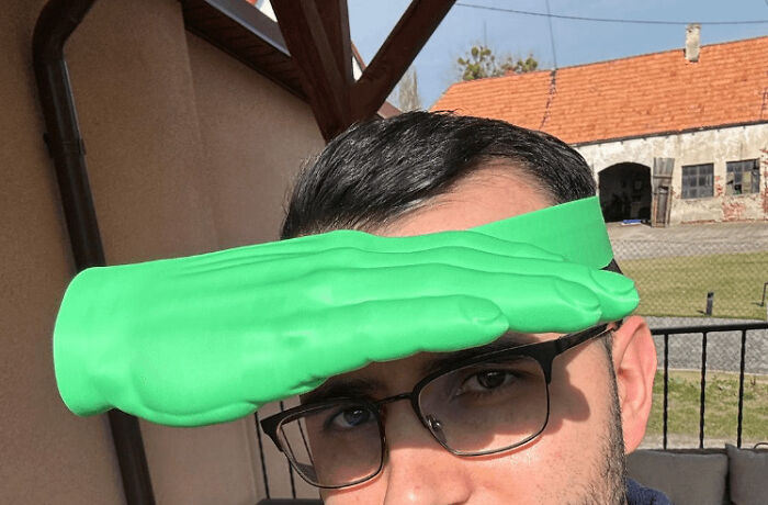 A man wearing a neon green 3D printed hand visor, an amusing and cool 3D print project.