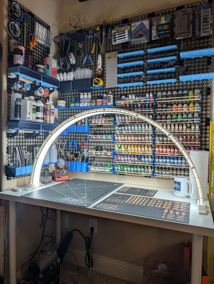 A well-organized craft desk with numerous paints and tools, featuring 3D printed storage solutions.