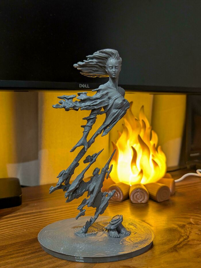 A detailed 3D printer project of a female figure with flowing hair, appearing to rise from a base, illuminated by a warm glow.
