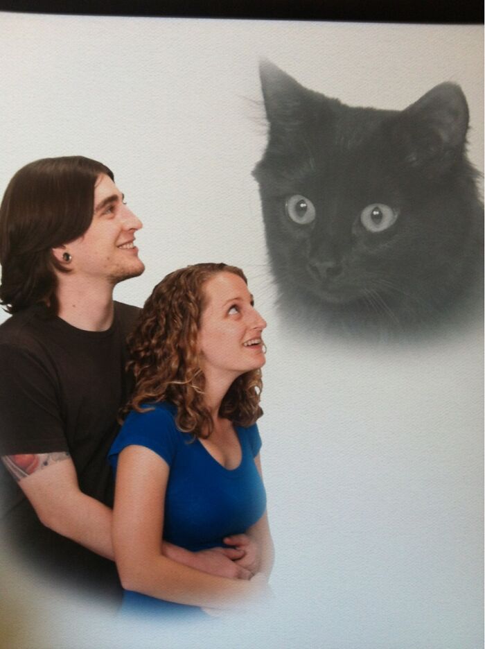A couple gazes up at a floating image of a black cat, one of the funniest animal photos.