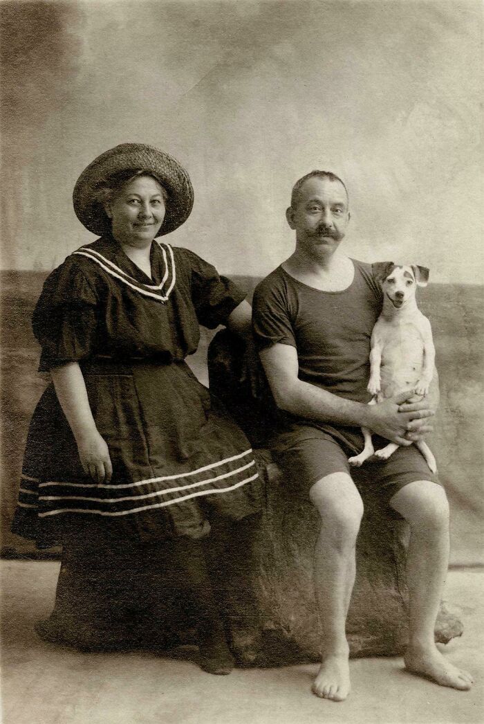 An old photo of a couple in swimsuits holding a small, funny animal, a dog.