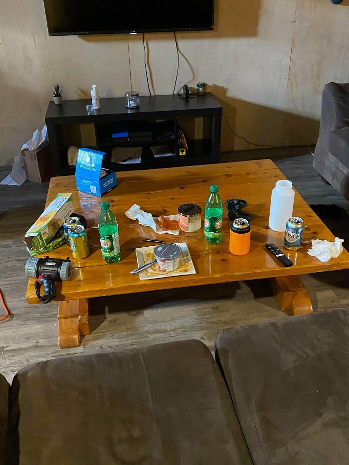A messy living room coffee table cluttered with food and drinks, displaying the behavior of entitled men.