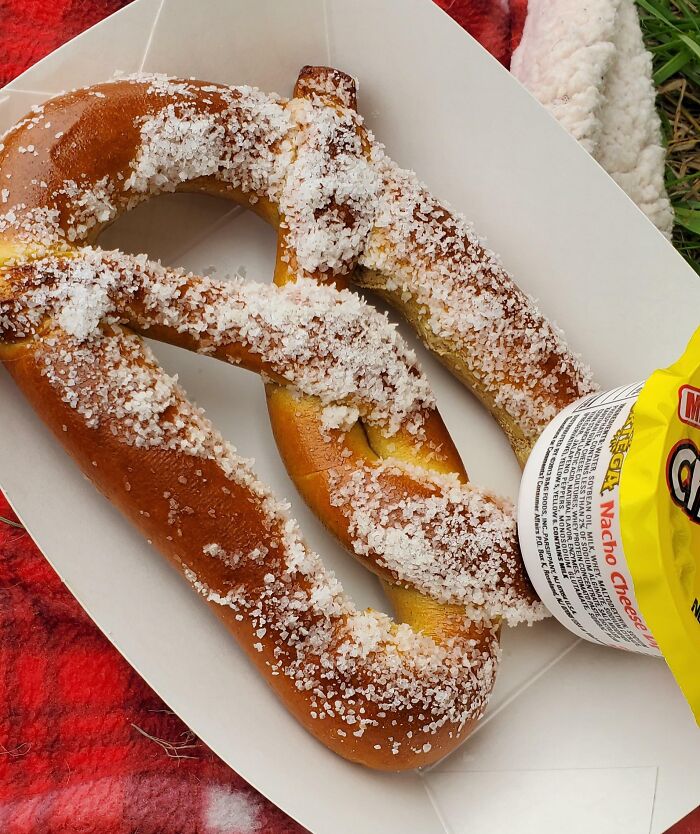 A large salted pretzel with a nacho cheese dip, representing stories of entitled men.
