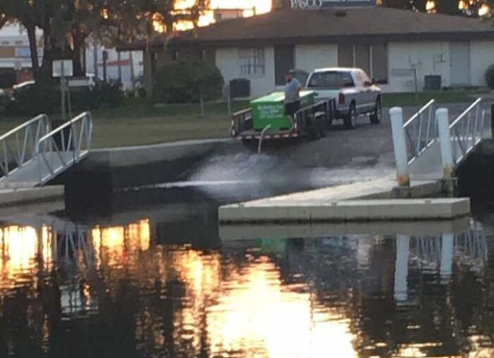 A man reversing a truck and trailer into a lake, creating a large splash, an example of entitled men ignoring boundaries.