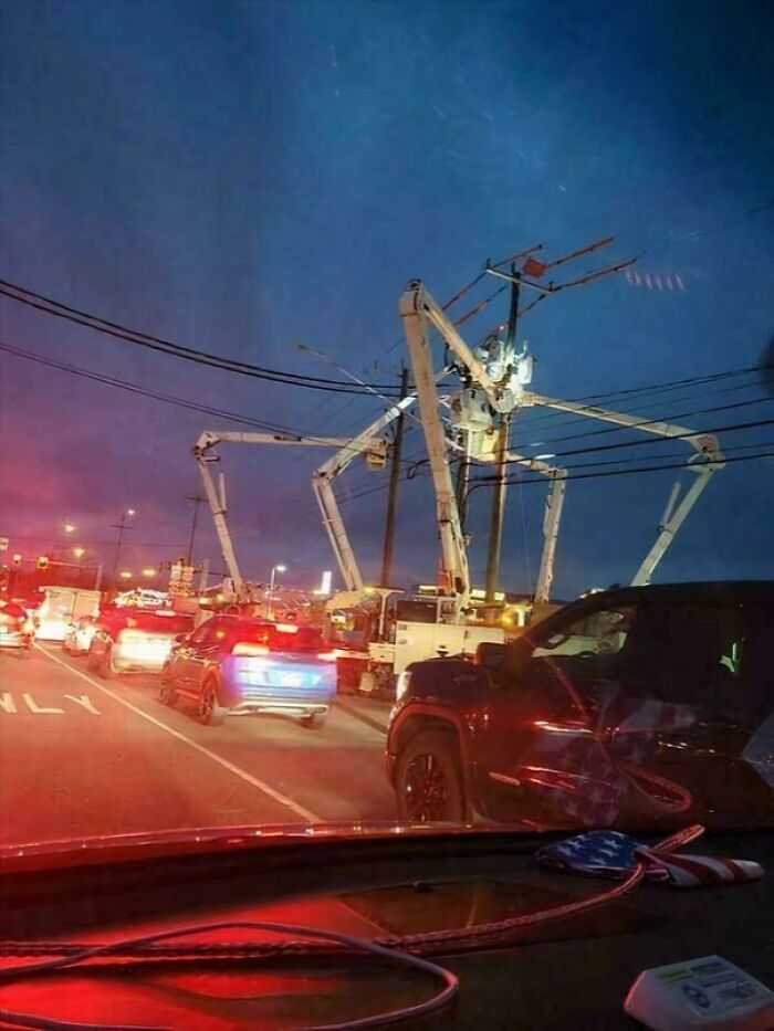 Extremely large utility boom lifts working on power lines at dusk, their forms resembling a giant spider, showing why large things can be scary and eerie.