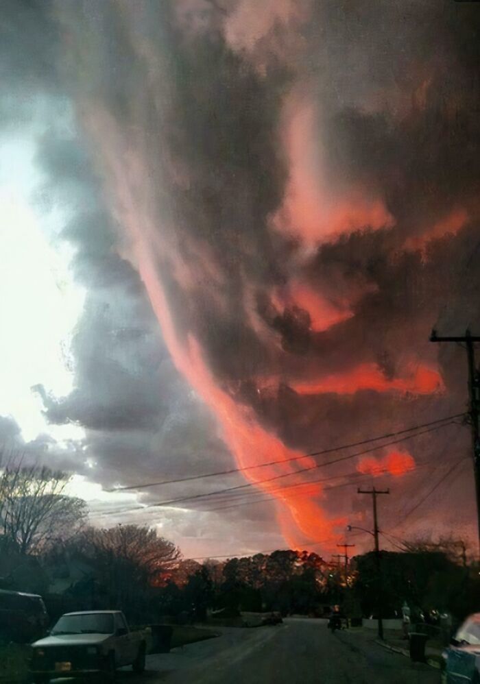 Extremely large eerie red cloud formation over a neighborhood at dusk, showcasing scary atmospheric phenomena.