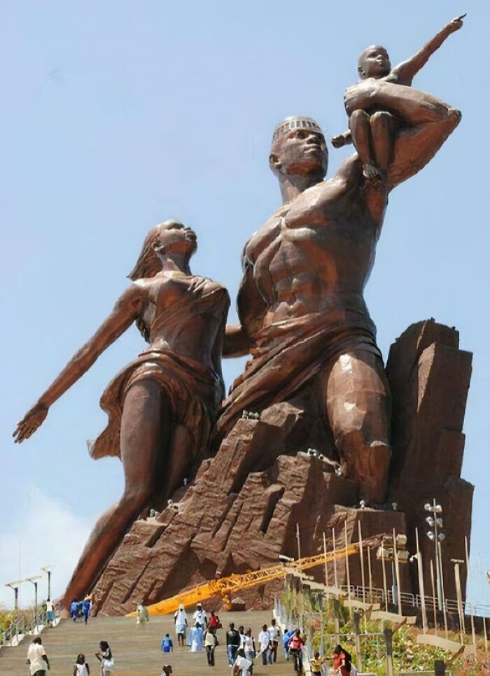 An eerie, extremely large monument of a family, emphasizing the grand scale of the statue against a clear sky.