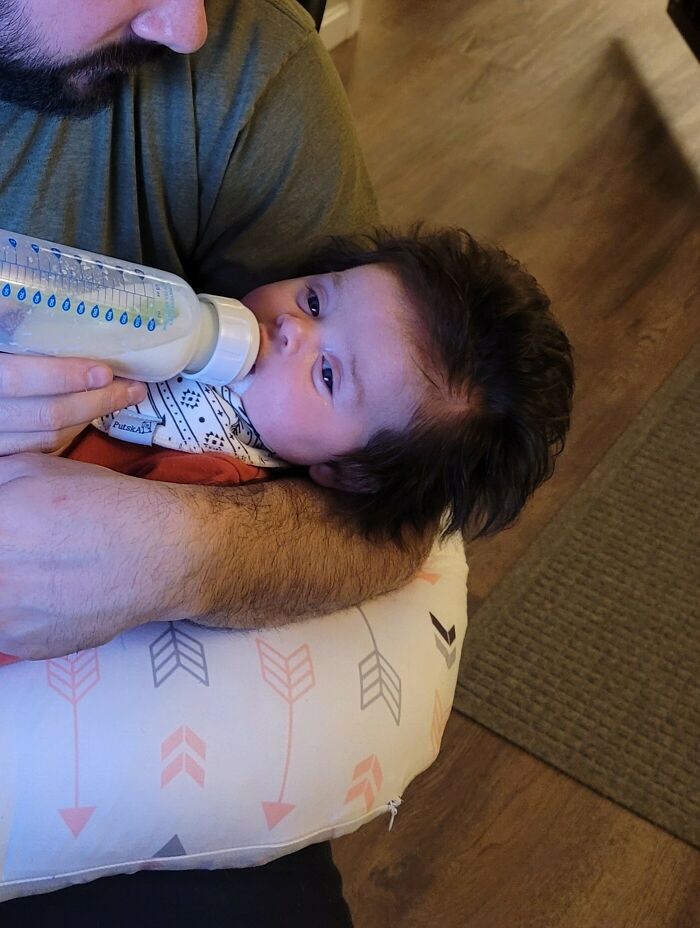 A parent bottle-feeding a newborn, showing the amazing human body at its earliest stage.