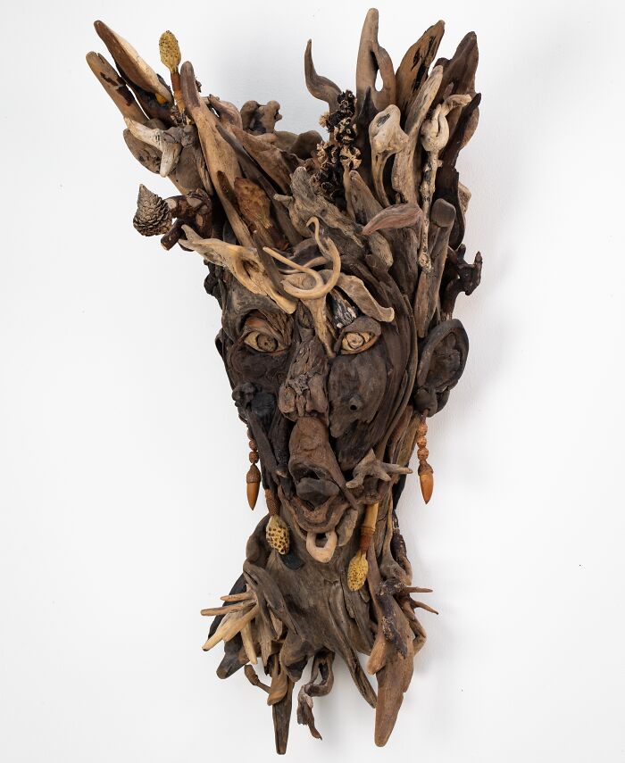 An artistic sculpture of a face crafted from collected pieces of wood, showcasing unique forms and organic elements.