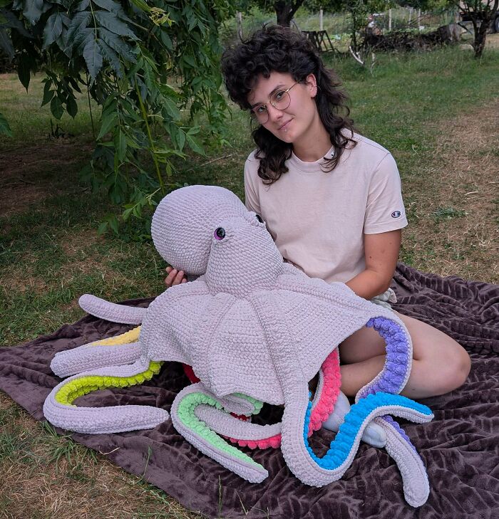 Person sitting outdoors with giant crochet octopus plush
