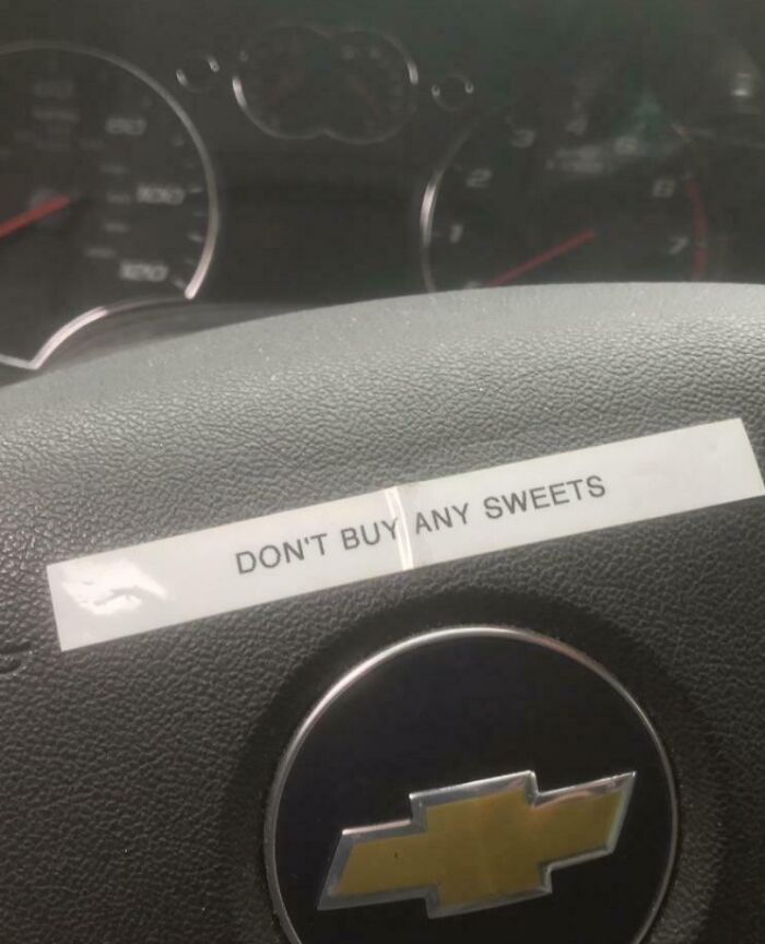 Car mechanics find a fortune cookie message saying DON'T BUY ANY SWEETS taped to a Chevrolet car steering wheel.