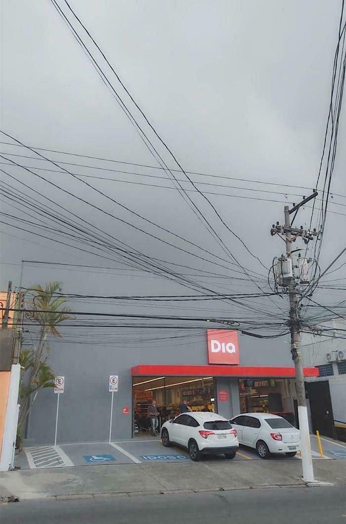 A Dia supermarket with a perfectly matched gray and red exterior under a cloudy sky. A satisfying paint match.