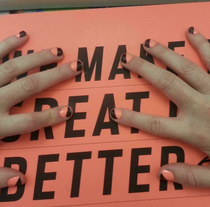 Two hands with peach and black nails matching the peach and black text on a sign, a satisfying paint match.
