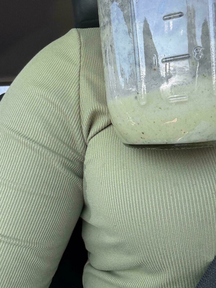 A person wearing a light green ribbed sweater with a jar of green smoothie that is a perfect paint match, creating a satisfying paint match.