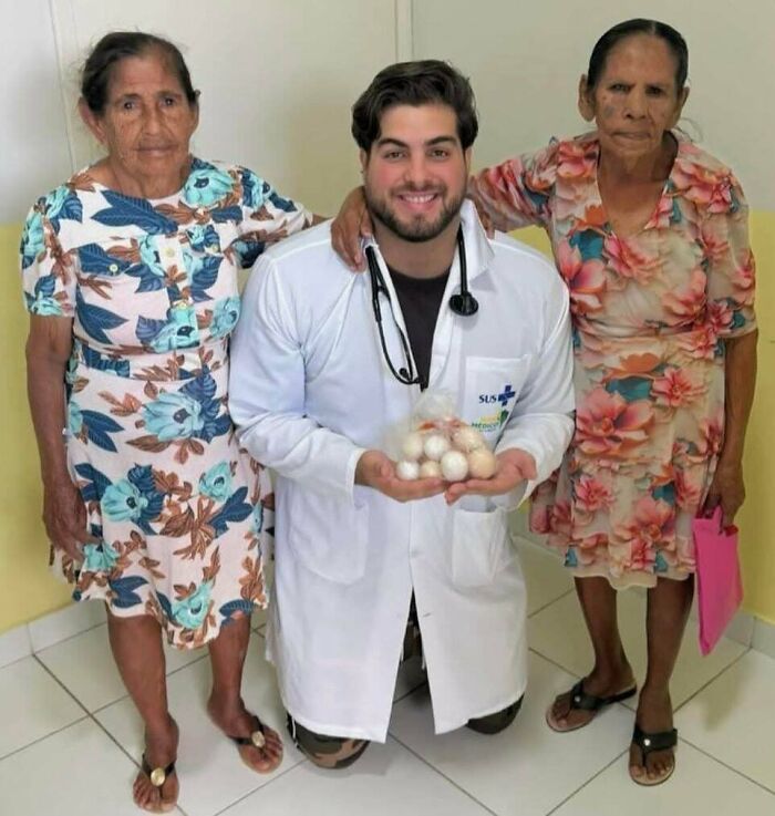 Aww-worthy photo: a smiling doctor kneels with eggs, flanked by two older women, lifting spirits.