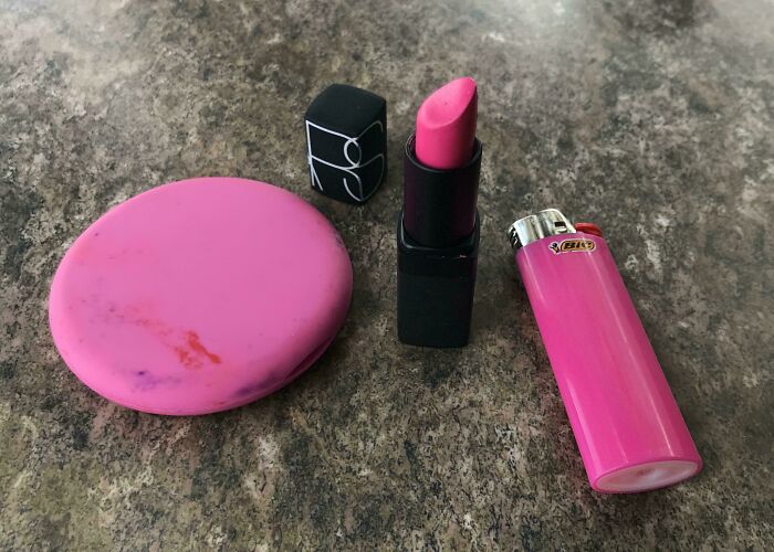 A pink compact, a pink lipstick, and a pink lighter on a speckled surface, illustrating satisfying paint matches.