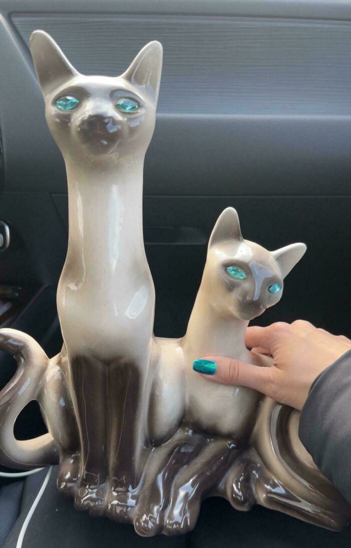 A hand with teal nails next to two Siamese cat figurines with blue eyes, demonstrating satisfying paint matches.