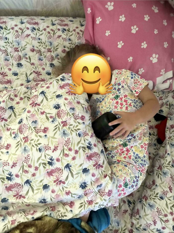 A child with an emoji over their face, sleeping in floral pajamas that perfectly match their floral duvet cover, showcasing satisfying paint matches.