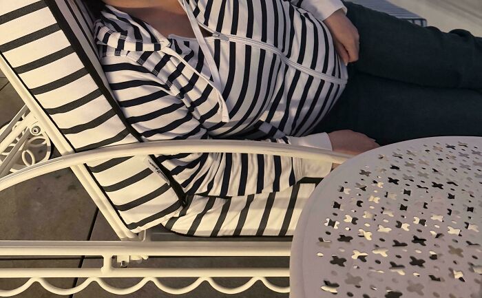A person in a black and white striped top lying on a lounge chair with striped cushions, showcasing satisfying paint matches.