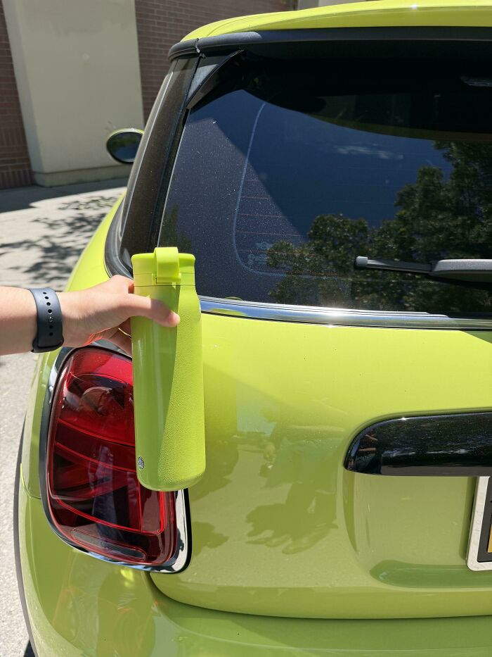 A hand holding a vibrant green water bottle perfectly matching the lime green paint of a car, showcasing satisfying paint matches.