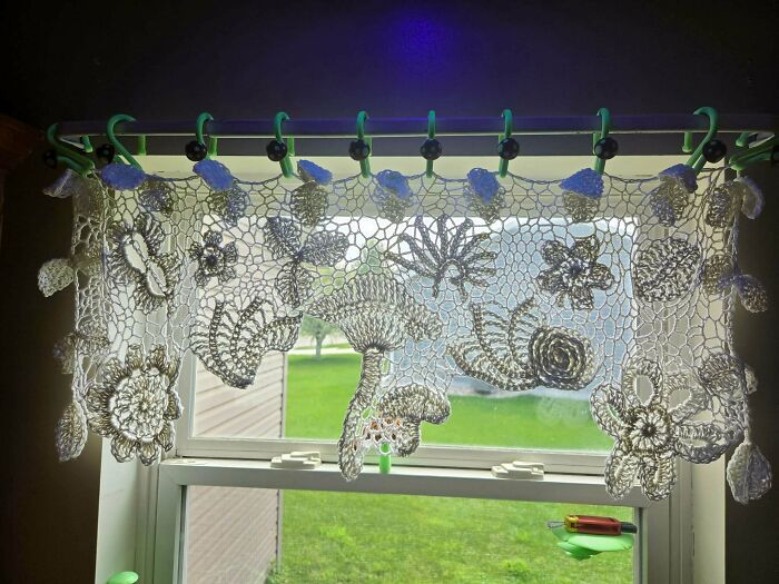 Intricate crochet lace curtain with floral designs hanging in window
