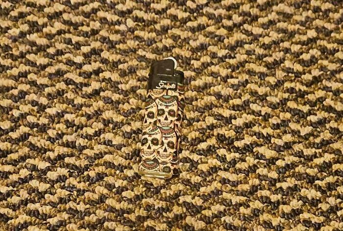 A lighter with a skull pattern perfectly matches the intricate pattern of a brown and beige carpet, showcasing satisfying paint matches.