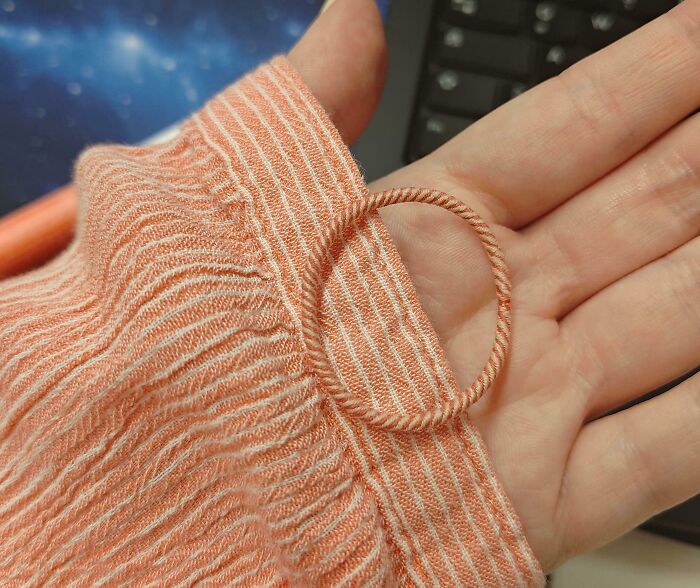 A hand holding a piece of striped fabric with a perfect paint match to a circular cord, creating a satisfying paint match.