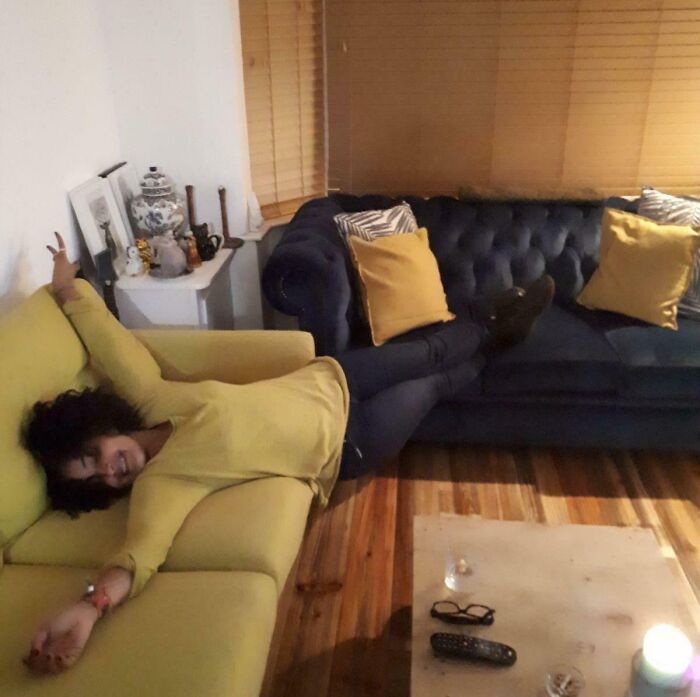 A woman perfectly matching her yellow shirt and green pants to her yellow and green sofas, a satisfying paint match.