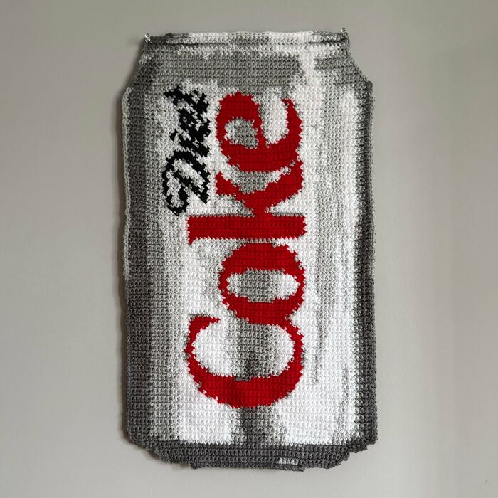Crochet art of a Diet Coke can hanging on a wall