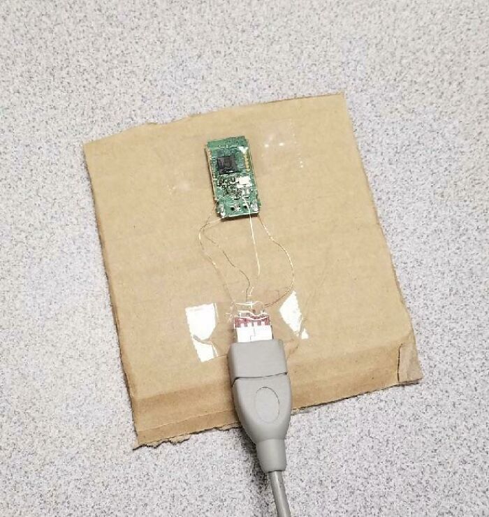 A circuit board attached to a cardboard piece, connected to a USB cable, showing a wild way to fix something.