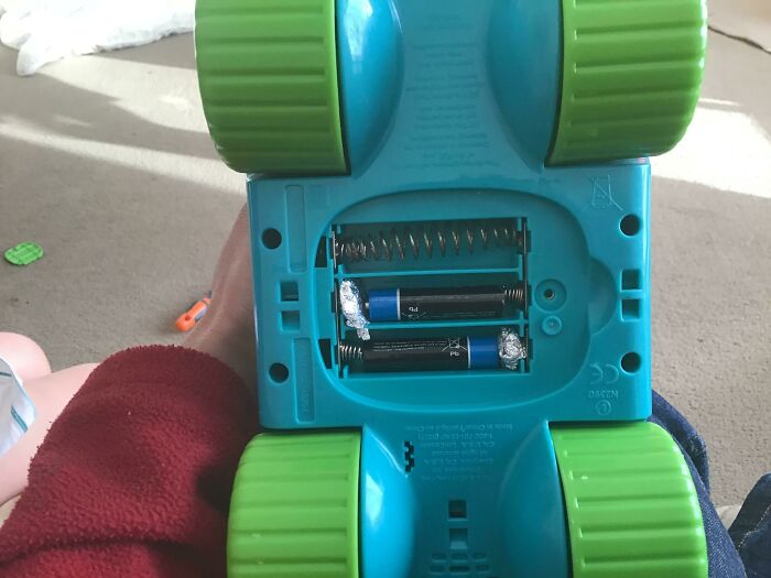 Aluminum foil and a spring replace batteries inside a toy, showing a wild way to fix something.
