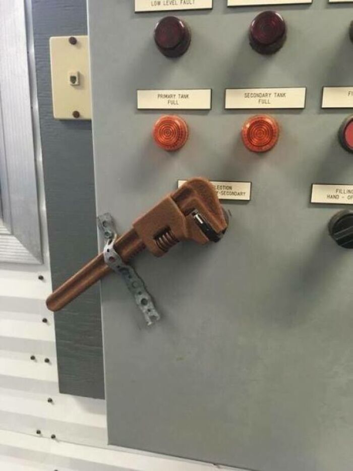 An adjustable wrench is strapped to a control panel, demonstrating an unhinged way to fix something.