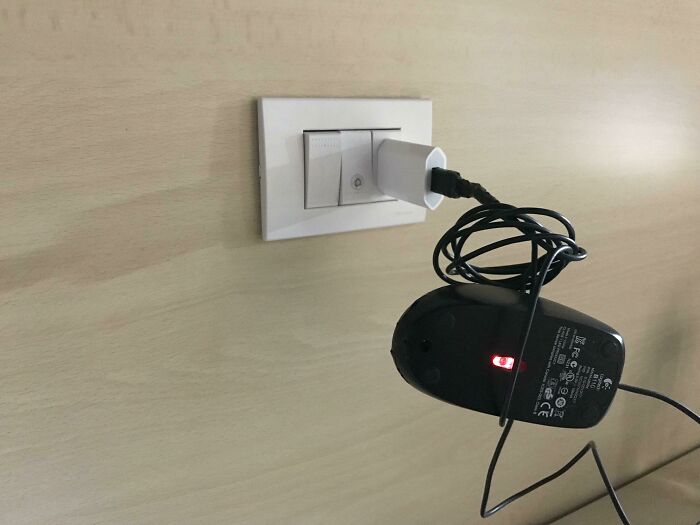 Wild and unhinged way to fix a computer mouse by plugging its charger into a wall socket.